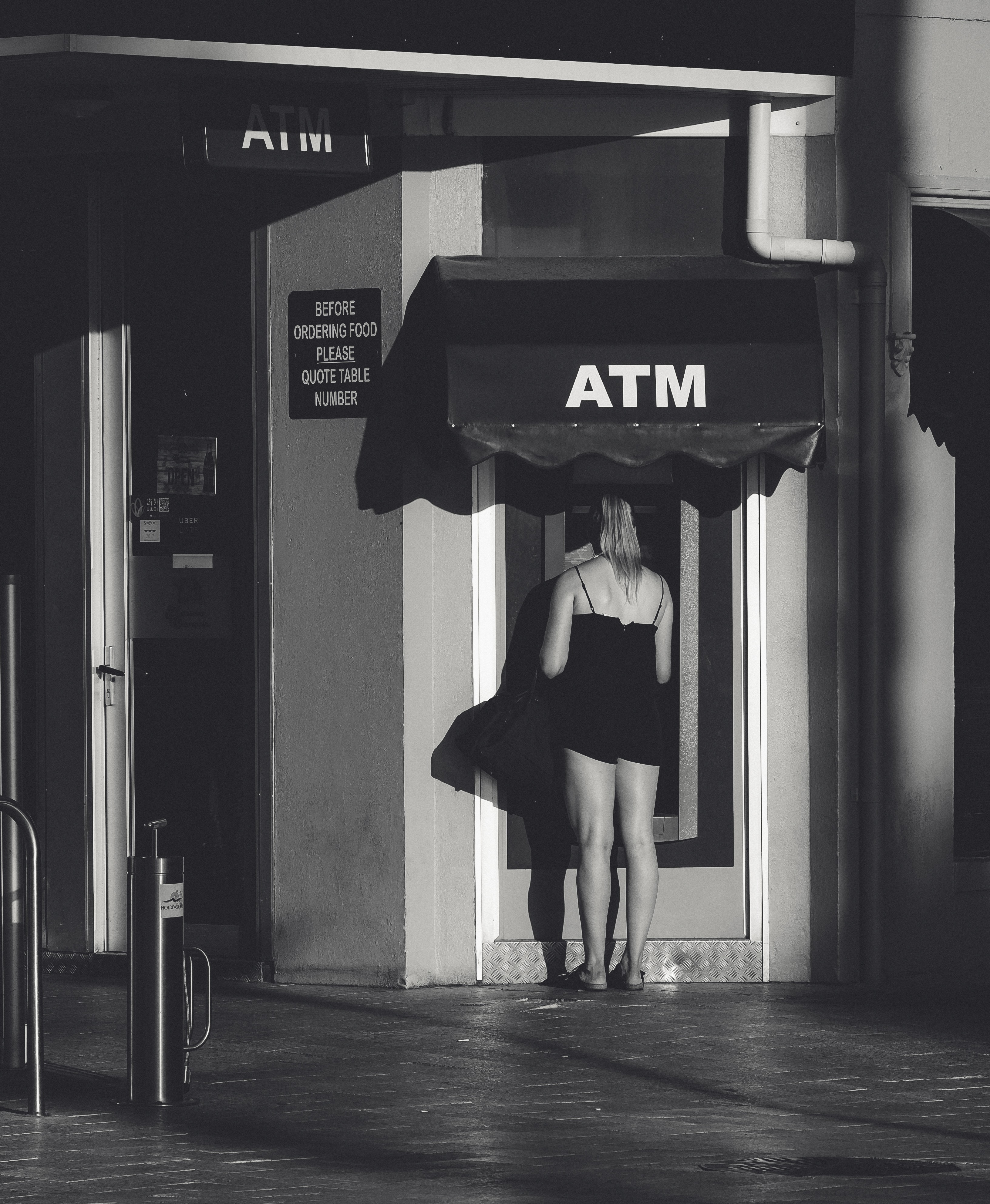 black and white photo of a young woman at the ATM