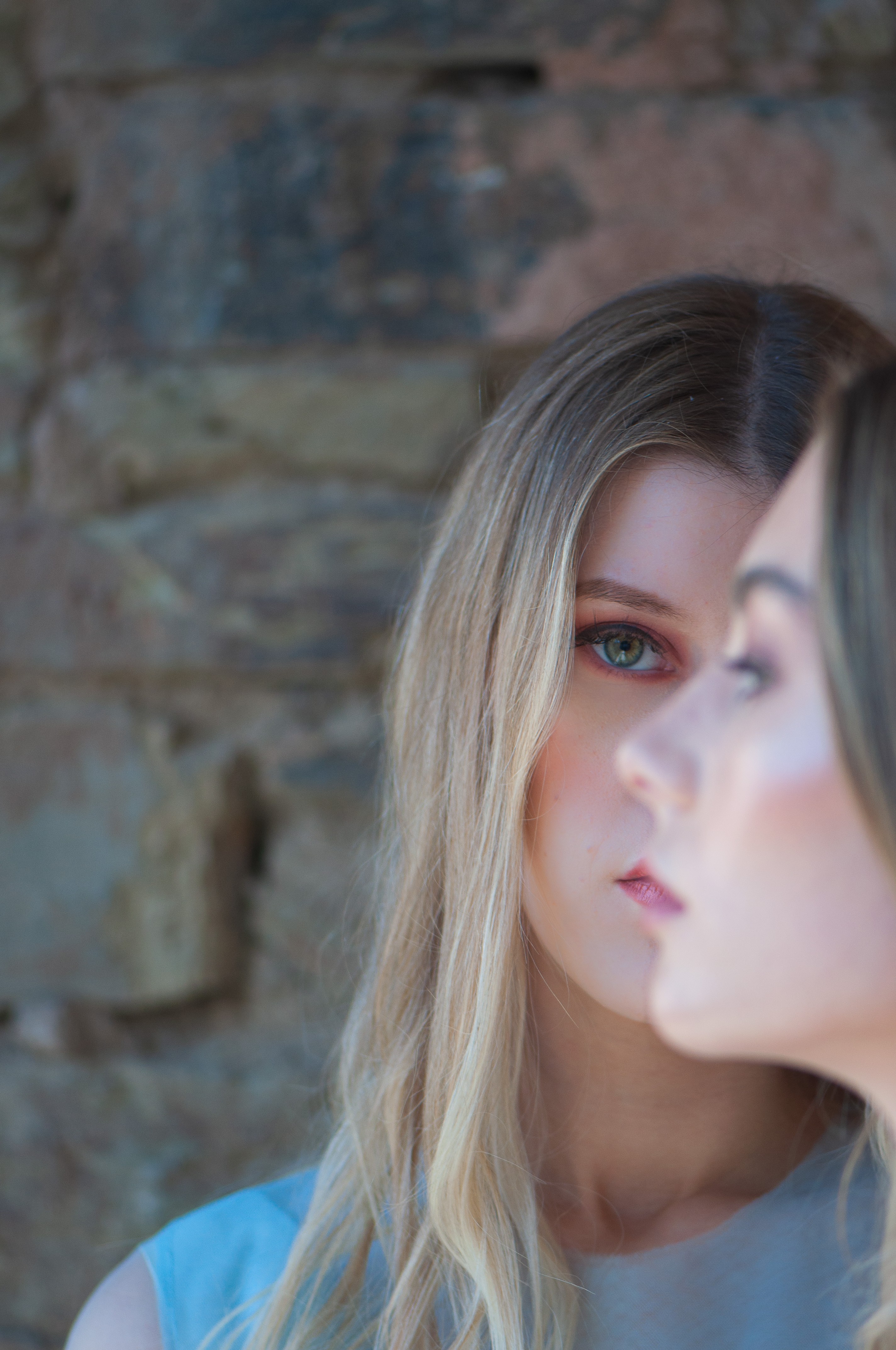 Portraits of two women in front of each other, one facing the camera and the other looking away.